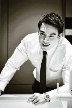 ภาพถ่ายขาวดำช่วงเวลาพักผ่อนหลังจบงาน ชายสวมเสื้อเชิ้ตและเนคไท ยืนจิบไวน์ในบรรยากาศสบาย ๆ